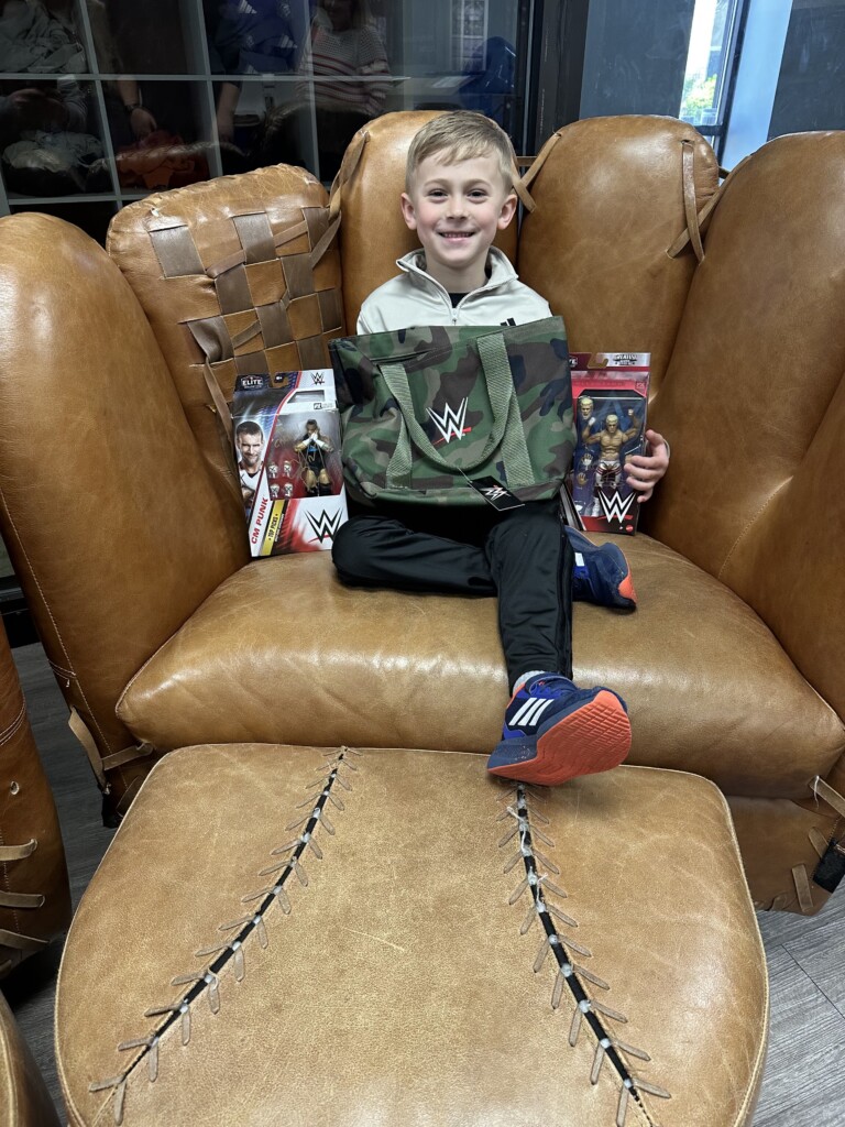 Smiling child with WWE-themed birthday gifts at BVSA