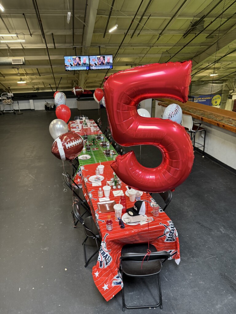 Fifth birthday sports party table with a large red number five balloon at BVSA